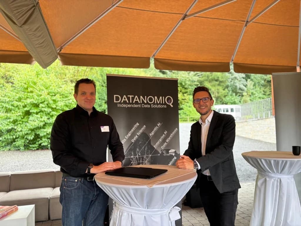 Zwei Kolleginnen oder Kollegen von DATANOMIQ bei einem Outdoor-Event neben einem Firmenbanner.